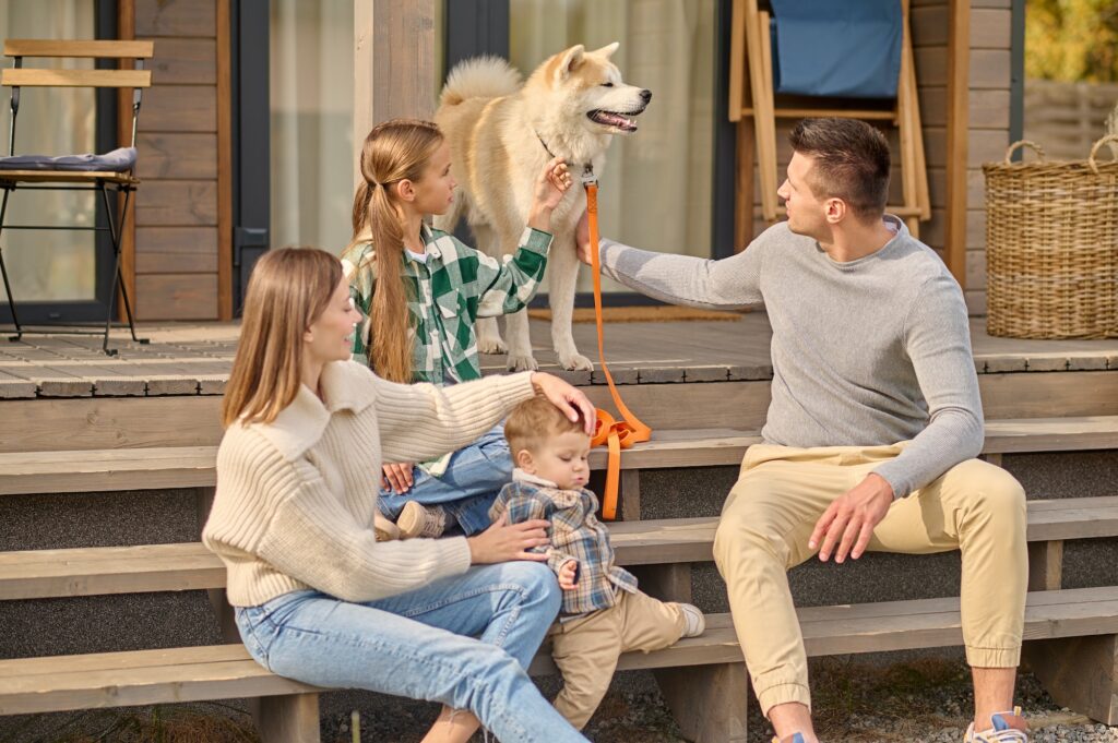 Girl and man touching dog and woman with child